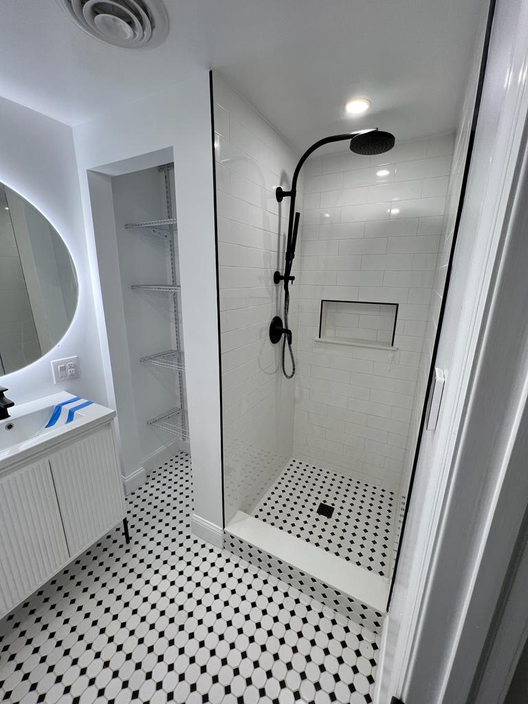 Walk-in shower with black fixtures, recessed niches and mosaic floor